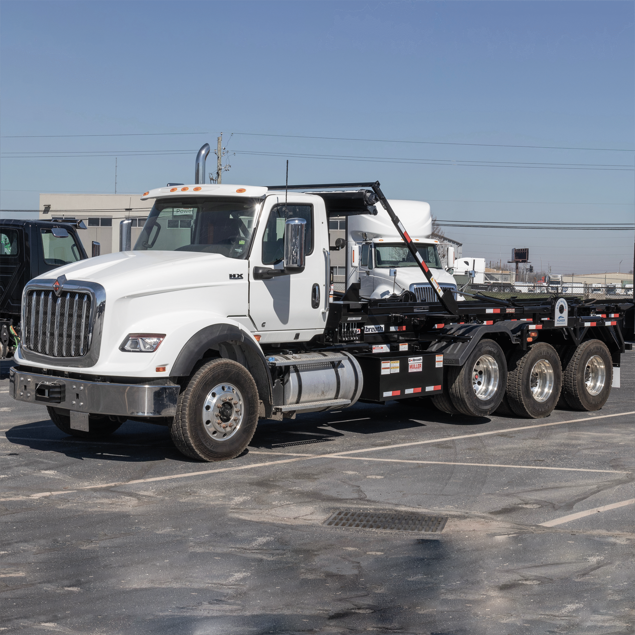 Camión roll off International modelo HX, especializado en transporte de cargas pesadas y contenedores industriales. Cuenta con gancho hidráulico que facilita la carga y descarga de cajas roll off, ideal para construcción, gestión de residuos y logística de materiales. Fotografía adecuada para catálogos de equipos pesados, servicios de renta de vehículos industriales y contenidos técnicos del sector transporte y construcción.